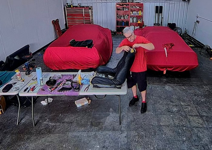 Work under way in the shop: a technician at the bench with two covered cars alongside.